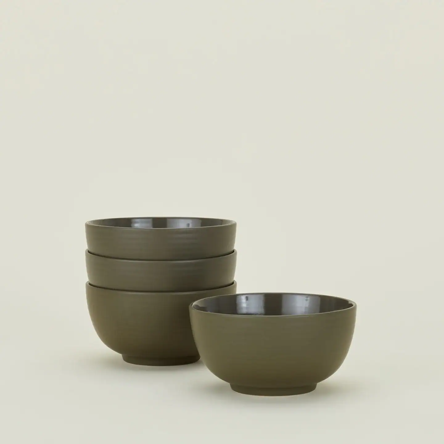 Four olive green ceramic bowls, three stacked on the left and one placed separately on the right, set against a plain light background.